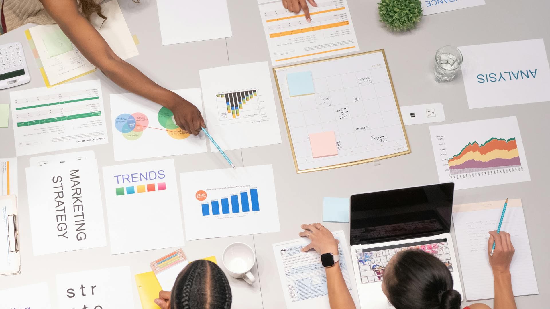 Overhead view of analysis documents, strategy sheets, and charts on a workspace