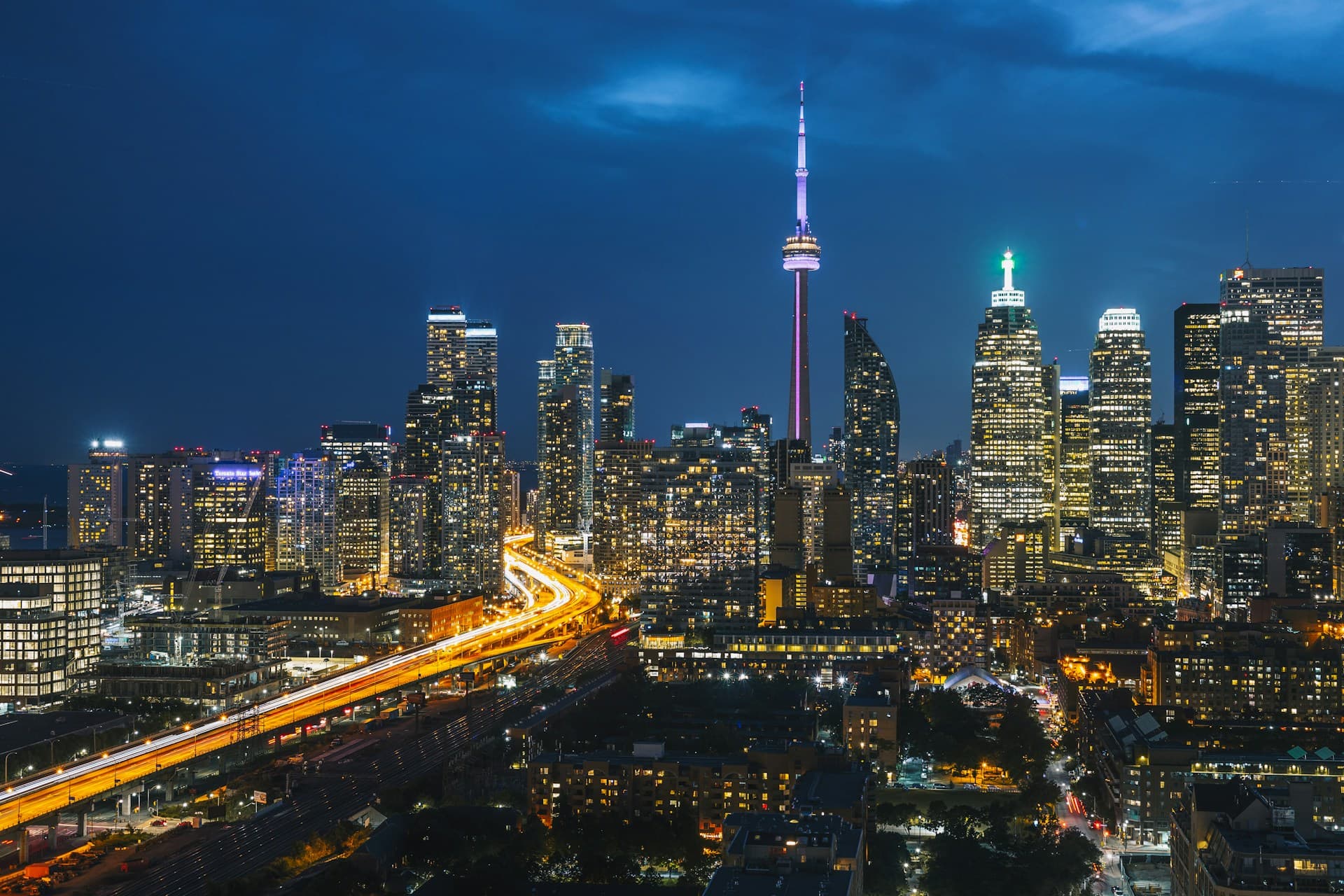 Aerial view of downtown Toronto's skyline at dusk, warm amber light across glass towers